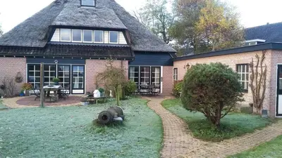 a large brick house with a thatched roof at Le-Clochard in Groet
