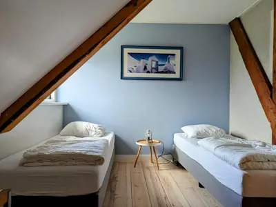 two beds in a room with blue walls at Le-Clochard in Groet