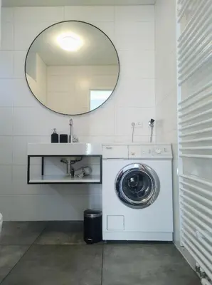 a washing machine in a bathroom with a mirror at Le-Clochard in Groet