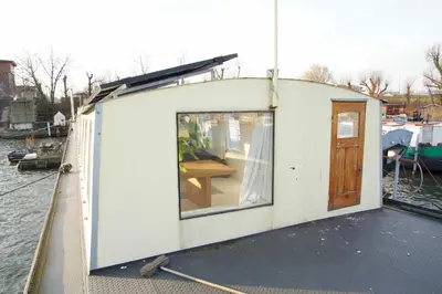 a small house on a boat in the water at The Island Houseboat in Amsterdam