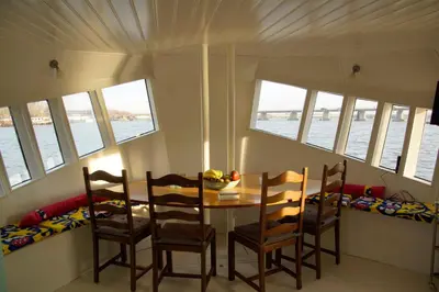 a dining room with a table and chairs and the water at The Island Houseboat in Amsterdam