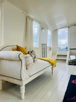 a white couch in a room with windows at The Island Houseboat in Amsterdam