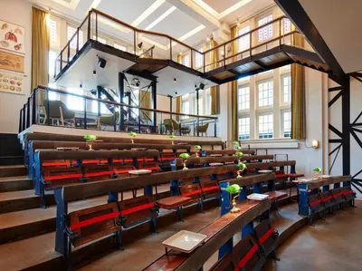 a large room with wooden tables and red chairs at Generator Amsterdam in Amsterdam