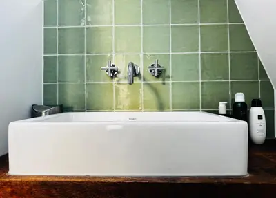 a white tub in a bathroom with green tiles at Betty Blue Bed & Breakfast in Gouda