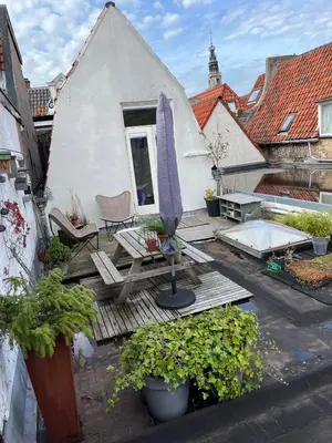 a patio with an umbrella and a table and chairs at At Loum in Alkmaar