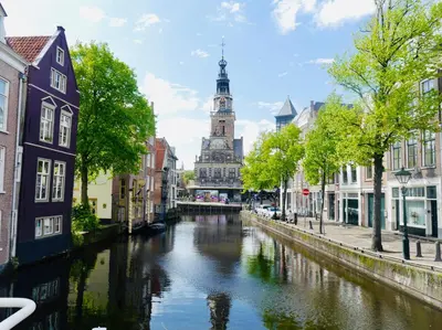 a river in a city with a clock tower at At Loum in Alkmaar