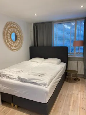 a bed in a bedroom with a mirror on the wall at Studio Lief Bergen binnen, bij bos duin en dorp in Bergen