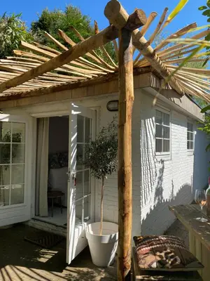 a wooden pergola with a potted plant on a patio at Studio Lief Bergen binnen, bij bos duin en dorp in Bergen