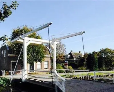 a wooden boardwalk with a white structure in front of a house at House of Cocagne in Kockengen