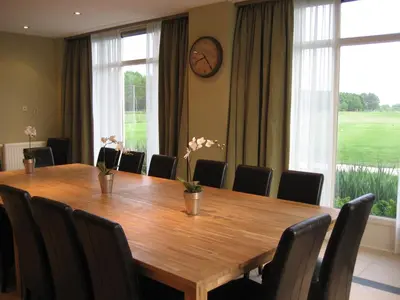 a dining room table with chairs and a clock on the wall at Hotel Beemster in Middenbeemster