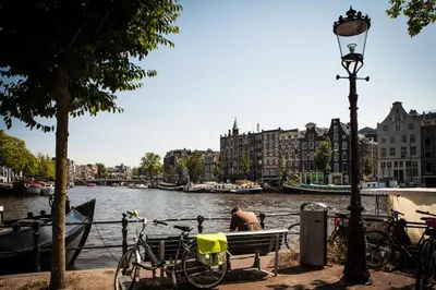 a bike parked next to a bench next to a river at Zwanestein Canal House in Amsterdam