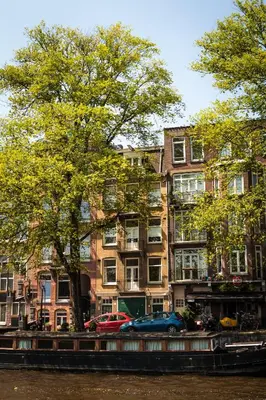a building with cars parked next to a river at Zwanestein Canal House in Amsterdam