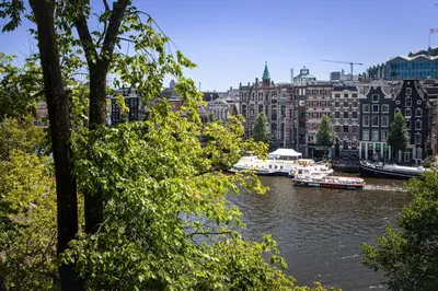 a river with boats in a city with buildings at Zwanestein Canal House in Amsterdam