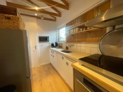 a kitchen with white cabinets and a black appliance at Kust 1 in Egmond aan Zee