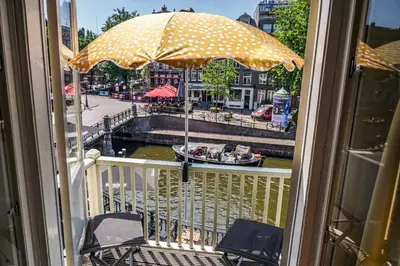 a balcony with two chairs and an umbrella at The Balcony at Prinsen Canal apartment Amsterdam in Amsterdam