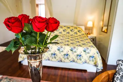 a vase of roses on a table with a bed at The Balcony at Prinsen Canal apartment Amsterdam in Amsterdam