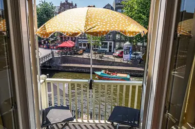 a view of a river with an umbrella on a balcony at The Balcony at Prinsen Canal apartment Amsterdam in Amsterdam