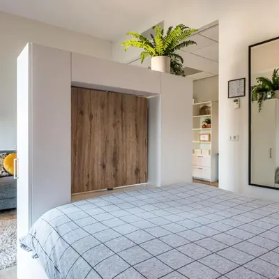 a bedroom with a large bed with a wooden door at JOINN! City Lofts Houten Utrecht in Houten