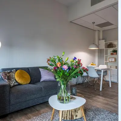 a living room with a couch and a vase of flowers on a table at JOINN! City Lofts Houten Utrecht in Houten