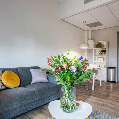 a living room with a couch and a vase of flowers at JOINN! City Lofts Houten Utrecht in Houten