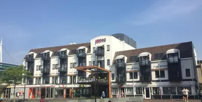 a large white building with a sign on it at JOINN! City Lofts Houten Utrecht in Houten