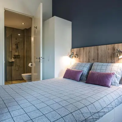 a bedroom with a large bed and a shower at JOINN! City Lofts Houten Utrecht in Houten