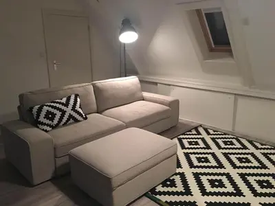 a living room with a couch and a stool at The Riverside Logies & Restaurant in Maarssen