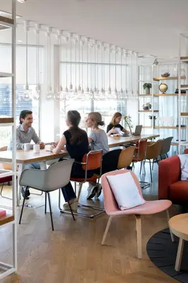 a group of people sitting at tables in a restaurant at Zoku Amsterdam in Amsterdam