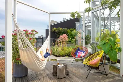 a woman sitting in a hammock on a balcony at Zoku Amsterdam in Amsterdam