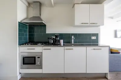 a kitchen with white cabinets and green tiles at Amsterdam Centre Harbour Apartments in Amsterdam