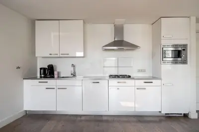 a white kitchen with white cabinets and a sink at Amsterdam Centre Harbour Apartments in Amsterdam