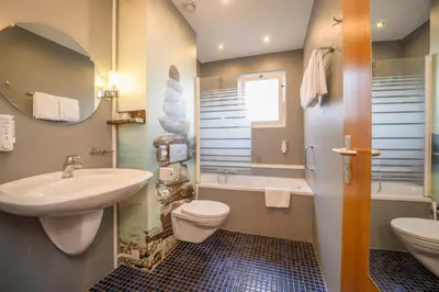 a bathroom with a sink and a toilet and a mirror at Fletcher Hotel Restaurant De Witte Raaf in Noordwijk
