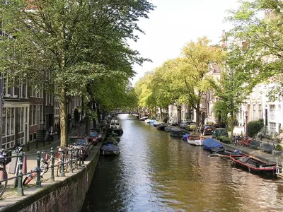 a canal with boats parked on the sides and buildings at B&B La Festa in Amsterdam
