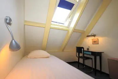 a bedroom with a bed and a desk and a window at Hotel Museumzicht in Amsterdam