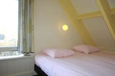 two pink pillows sitting on a bed next to a window at Hotel Museumzicht in Amsterdam