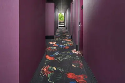 a hallway with purple walls and a colorful floor at Hotel Babylon Heerhugowaard - Alkmaar in Heerhugowaard