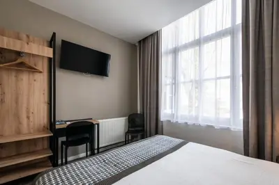 a hotel room with a bed and a desk and a television at Acostar Hotel in Amsterdam