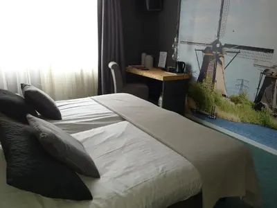a bedroom with a bed with a windmill picture on the wall at Hotel Villa Flora in Hillegom