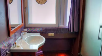 a bathroom with a sink and a window and a clock at Pension & Spa de Watertoren in Zandvoort