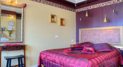 a bedroom with a bed with pink sheets and a mirror at Pension & Spa de Watertoren in Zandvoort