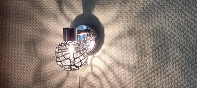 a light hanging on a wall with a shadow at Overbosch in Bilthoven
