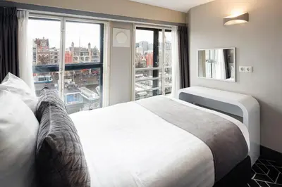 a bedroom with a white bed and a large window at Hotel CC in Amsterdam