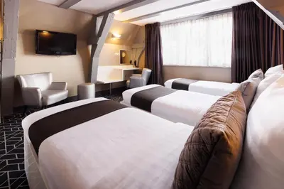 a hotel room with three beds and a television at Hotel CC in Amsterdam