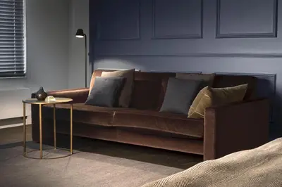 a brown couch with pillows and a table in a room at COMMUNE suites in Amsterdam