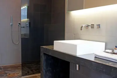 a bathroom with a white sink and a shower at COMMUNE suites in Amsterdam