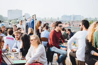 a crowd of people sitting at tables on a rooftop at Hotel Casa Amsterdam in Amsterdam