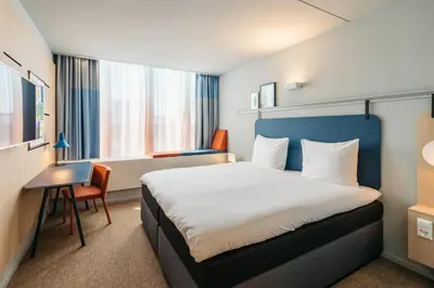 a hotel room with a bed and a desk and window at Hotel Casa Amsterdam in Amsterdam