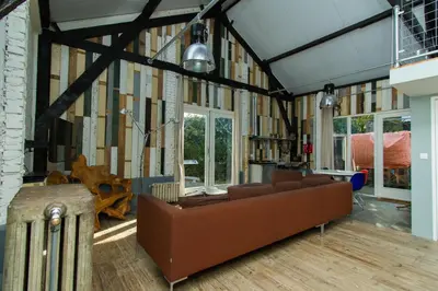 a living room with a couch and some windows at Paardenstal, Private House with wifi and free parking for 1 car in Weesp