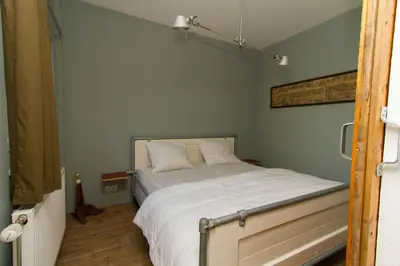 a bedroom with a bed with white sheets at Paardenstal, Private House with wifi and free parking for 1 car in Weesp