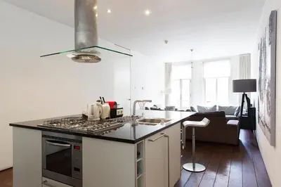 a kitchen with a stove top oven next to a living room at Marnix360apartments Modern in Amsterdam